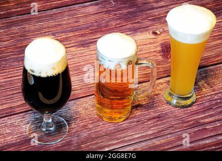 Trois verres différents avec différents types de bière, clair, foncé et blé sur une table en bois. Gros plan. Banque D'Images