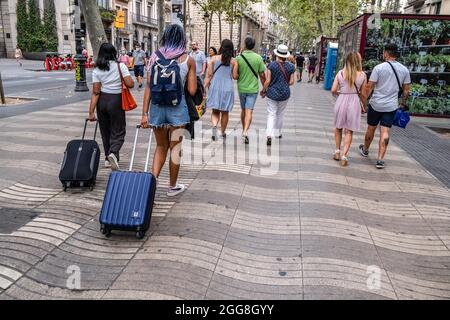 Barcelone, Espagne. 29 août 2021. Les touristes avec des valises à roulettes sont vus sur la Rambla à Barcelone. L'équilibre économique des secteurs économiques qui dépendent du tourisme a fermé en août en dessous des attentes en raison des restrictions de mobilité persistantes découlant de la soi-disant cinquième vague de Covid. Crédit : SOPA Images Limited/Alamy Live News Banque D'Images