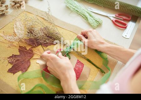 Mains de femme nouant le ruban sur le bouquet de fleurs séchées en faisant des œuvres d'art pour la décoration de la chambre Banque D'Images