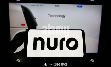 Personne tenant un téléphone portable avec le logo de la société américaine de robotique Nuro Inc. Sur l'écran en face de la page Web d'affaires. Mise au point sur l'affichage du téléphone. Banque D'Images