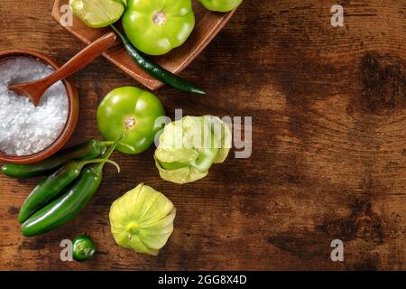 Tomatillos, tomates vertes et piments. Ingrédients de cuisine mexicaine sur fond de bois rustique foncé, plan de travail au plafond avec espace pour les copies Banque D'Images