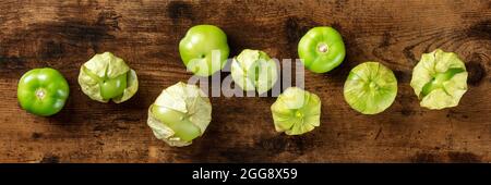 Tomatillos, tomates vertes, vue panoramique sur la surface plane. Ingrédients mexicains sur fond de bois rustique sombre Banque D'Images