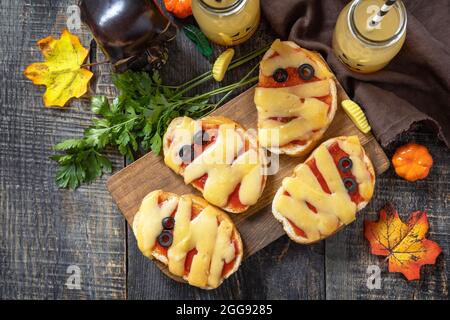 Nourriture de fête d'Halloween. Halloween momies mini pizzas sur une table en bois. Vue de dessus de l'arrière-plan de la mise à plat Banque D'Images