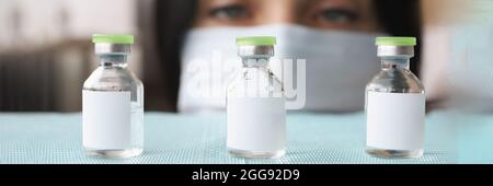 Femme pharmacien dans un masque médical de protection sélection de bouteilles en verre avec fermeture liquide Banque D'Images