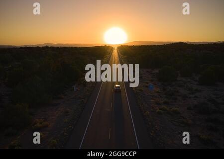 Voiture sur une autoroute allant directement au coucher du soleil à l'horizon, Utah, États-Unis Banque D'Images