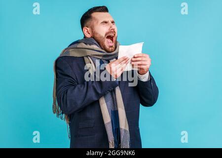 Toux ou éternuements. Homme malade enveloppé dans un foulard éternuant, toussant, se sentant mal, malade ou grippe, souffrant d'allergie ou de syndrome grippal saisonnier Banque D'Images