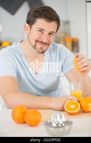 l'homme presse des oranges pour obtenir un jus d'orange Banque D'Images