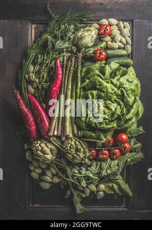 Beaucoup de légumes différents. Composition sur fond sombre avec artichauts fraîchement récoltés, salade, tomates, asperges, radis, mandarine verte , cu Banque D'Images