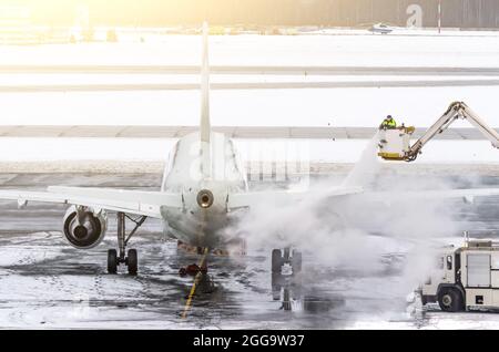 L'équipe au sol assure le dégivrage. Ils pulvérisent l'avion, ce qui empêche la formation de givre Banque D'Images