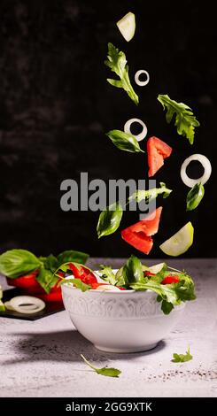 tandis que le bol avec les ingrédients de salade tombant Banque D'Images