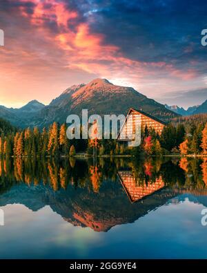 Vue d'automne pittoresque sur le lac Strbske pleso dans le parc national des Hautes Tatras, Slovaquie. Eau claire avec des reflets de mélèze d'orange et de hautes montagnes en arrière-plan. Photographie de paysage Banque D'Images