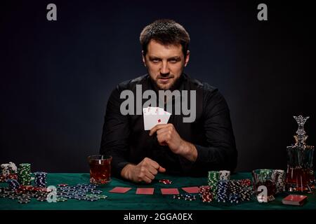 Joueur de casino barbu homme jouant au poker sur table verte Banque D'Images