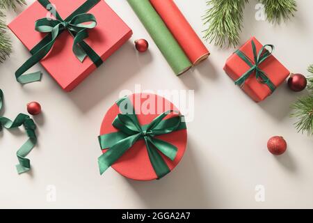 Fond de Noël avec boîtes-cadeaux rouges et vertes, rouleaux de papier sur un gris. Cadeau de préparation et d'emballage pour les vacances. Vue de dessus. Lendemain de Noël. Banque D'Images