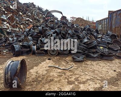 Une pile de jantes de voiture cassées dans un jardin. Jantes de voiture métalliques usées prêtes pour le transport pour le recyclage et la fonte. Recyclage des ressources et recyclage Banque D'Images