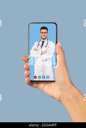 Smartphone portable avec Male Doctor à l'écran, fond bleu Banque D'Images