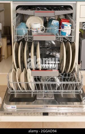 Un lave-vaisselle équipé plein de vaisselle propre lavée, des tasses et de la vaisselle dans une cuisine domestique à la maison Royaume-Uni, Grande-Bretagne Banque D'Images