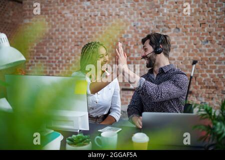 Jeunes gens d'affaires joyeux assis et travaillant à un bureau au bureau, concept de coopération. Banque D'Images