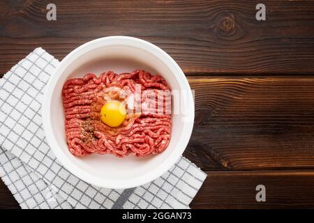 Bœuf haché cru ou bœuf haché dans un bol blanc sur fond de bois. Vue de dessus, espace de copie pour le texte Banque D'Images
