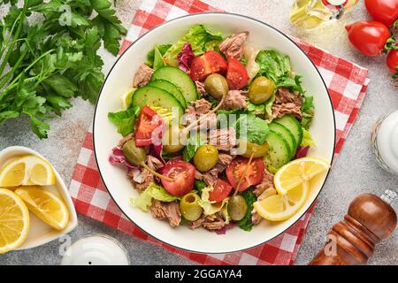 Salade de thon avec légumes frais, olives, câpres et citron servie dans un bol sur fond gris clair. Vue de dessus avec espace de copie. Banque D'Images