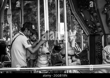 SUBIC, PHILIPPINES - 09 août 2017 : une échelle de gris d'un père prenant soin de sa fille dans un carrousel de Subic Bay à Olongapo City, Zambals, Philippines Banque D'Images