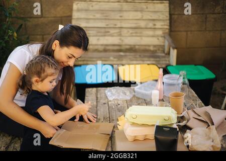 La famille triant les ordures à la maison sur l'arrière-cour. Concept de recyclage à l'extérieur. Maman et fille se soucier de la nature Banque D'Images