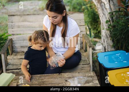 La famille triant les ordures à la maison sur l'arrière-cour. Concept de recyclage à l'extérieur. Maman et fille se soucier de la nature Banque D'Images