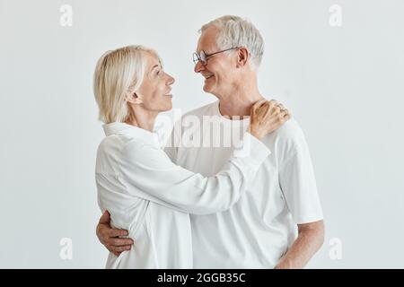 Portrait minimal de couple senior moderne avec un arrière-plan blanc et regardant l'un l'autre Banque D'Images