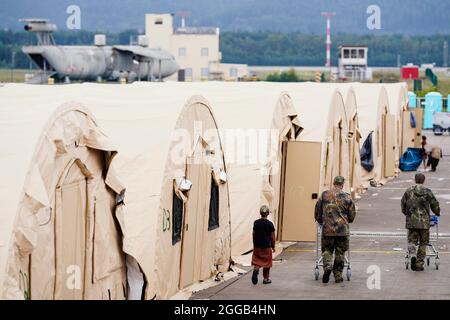 Ramstein Miesenbach, Allemagne. 30 août 2021. LES soldats AMÉRICAINS marchent devant une rangée de tentes avec des chariots à la base aérienne de Ramstein. Les États-Unis utilisent également leur base militaire à Ramstein, dans le Palatinat, comme centre d'évacuation des demandeurs d'abris et des forces locales d'Afghanistan. Credit: Uwe Anspach/dpa/Alamy Live News Banque D'Images