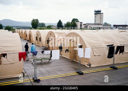 Ramstein Miesenbach, Allemagne. 30 août 2021. Les personnes évacuées d'Afghanistan se tiennent entre des tentes à la base aérienne de Ramstein. Les États-Unis utilisent également leur base militaire à Ramstein, dans le Palatinat, comme un centre d'évacuation des personnes cherchant à se protéger et des forces locales d'Afghanistan. Credit: Uwe Anspach/dpa/Alamy Live News Banque D'Images