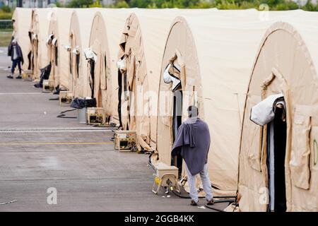 Ramstein Miesenbach, Allemagne. 30 août 2021. Un homme évacué d'Afghanistan se trouve parmi une rangée de tentes à la base aérienne de Ramstein. Les États-Unis utilisent également leur base militaire à Ramstein, dans le Palatinat, comme centre d'évacuation des demandeurs d'abris et des forces locales d'Afghanistan. Credit: Uwe Anspach/dpa/Alamy Live News Banque D'Images