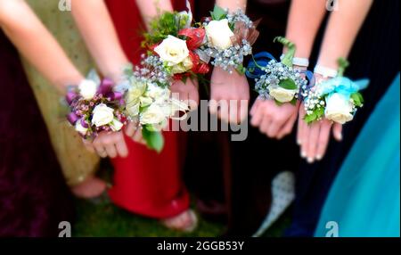 Filles tenant les bras dehors avec des fleurs de fleur pour le bal école secondaire danse romance amusant nuit fête selctive focus flou Banque D'Images