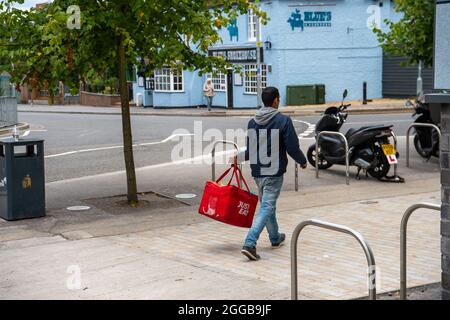 Bracknell, Berkshire, Royaume-Uni. 28 août 2021. Un homme porte un récipient juste manger prêt à faire une livraison de nourriture. Crédit : Maureen McLean/Alay Banque D'Images