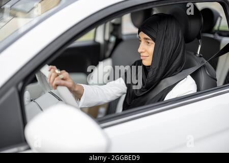 Une femme musulmane conduit une voiture Banque D'Images