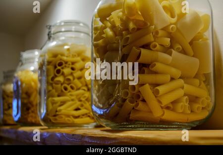 Quatre bocaux en verre se tenant sur la tablette et remplis de divers types de pâtes. Banque D'Images