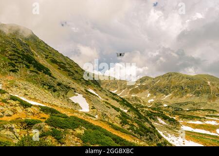 Photographie d'un petit drone planant au-dessus du sol dans un environnement de montagne. Encore d'un petit drone Banque D'Images