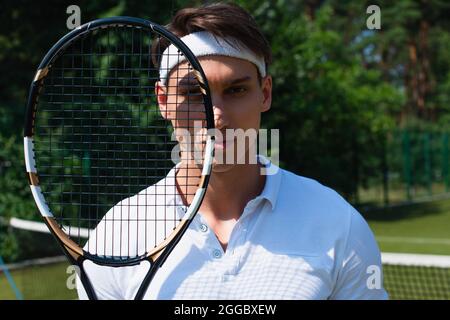 Jeune sportif tenant une raquette de tennis et regardant la caméra Banque D'Images