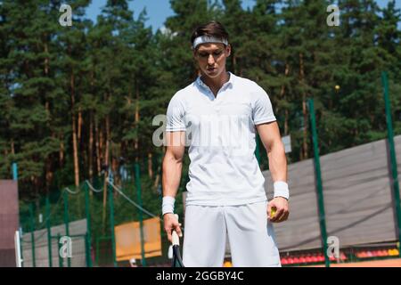 Jeune sportif tenant une raquette et un ballon de tennis en plein air Banque D'Images