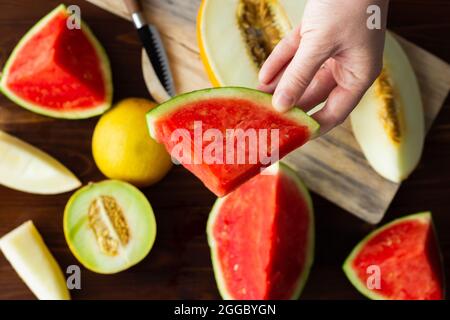 Main tenant une tranche de pastèque; variété de melons Banque D'Images