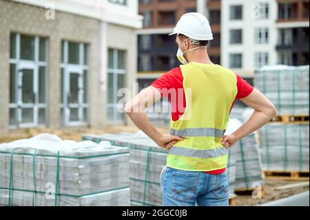 Constructeur regardant les briques empilées sur les palettes en bois Banque D'Images