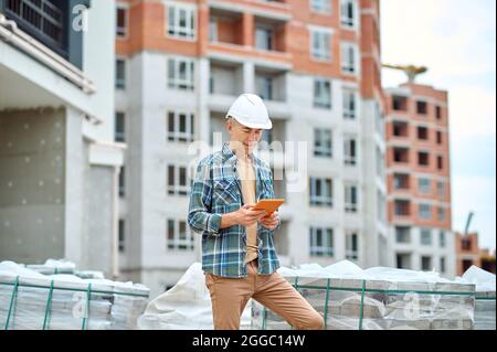 Ingénieur de construction concentré regardant le gadget dans ses mains Banque D'Images