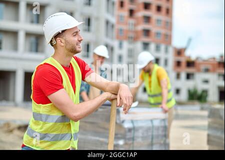 Joyeux constructeur dans un casque de sécurité prenant une pause de travail Banque D'Images