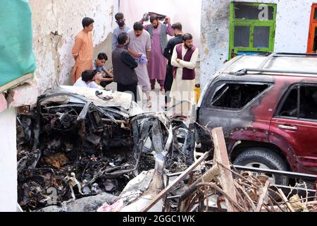 Kaboul, Afghanistan. 30 août 2021. Les résidents afghans et les membres de la famille des victimes se rassemblent à côté d'un véhicule endommagé à l'intérieur d'une maison, le lendemain d'une frappe aérienne par drone américain à Kaboul le lundi 30 août 2021. Cinq roquettes ont été lancées au début de lundi à l'aéroport de Kaboul, dans la capitale afghane, où l'évacuation des troupes américaines est en cours. Les roquettes attachées à une voiture ont été tirées vers l'aéroport à partir de la localité de Khair Khana Minia avant d'être frappées par un missile de drone américain a déclaré des témoins. Photo de Bashir Darwish/ Credit: UPI/Alay Live News Banque D'Images