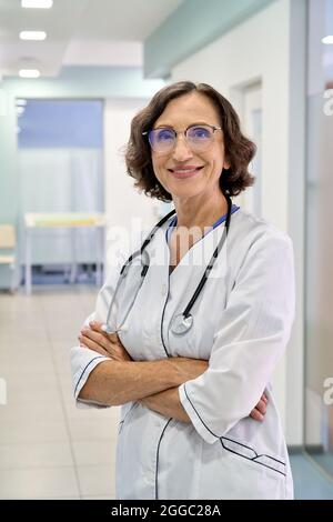 Portrait vertical de la femme médecin heureuse infirmière debout dans la clinique de l'hôpital. Banque D'Images