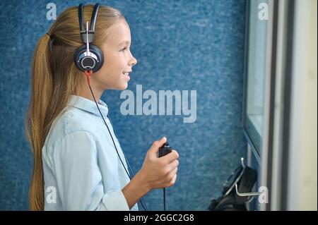 Fille souriante dans un casque dans la salle audiométrique Banque D'Images