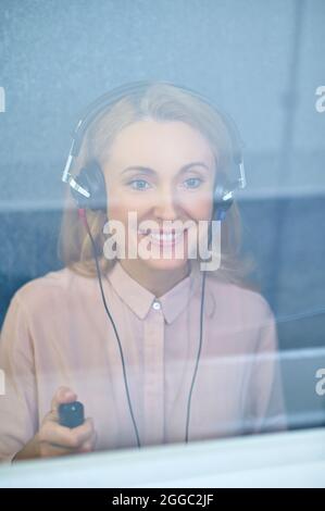 Femme blonde souriante dans un casque dans la salle audiométrique Banque D'Images