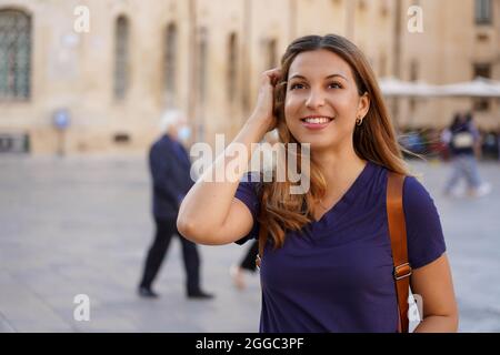 Portrait en gros plan d'une charmante femme latine joyeuse avec un sourire enjoué ayant une promenade dans une ville étrangère Banque D'Images