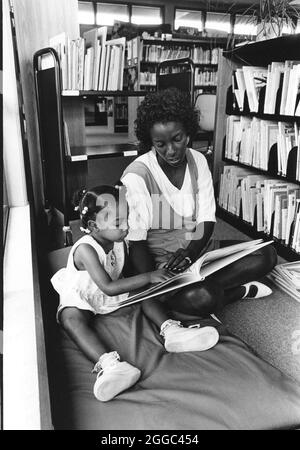 Austin Texas USA, 1992 : mère noire et enfant noir lisent ensemble pendant un programme de lecture estival dans une bibliothèque publique. ©Bob Daemmrich Banque D'Images