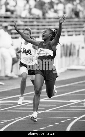 Austin, Texas USA, circa 1992 : fille afro-américaine exulte alors que le franchit la ligne d'arrivée en premier dans la course de 400 mètres au Texas State UIL High School Track Meet à l'Université du Texas à Austin. ©Bob Daemmrich Banque D'Images