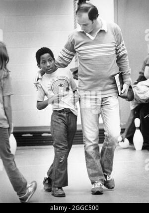 Austin Texas USA, 1984 : Patrick Skeaton, étudiant noir de quatrième année, qui a perdu sa jambe droite à cause du spina bifida, interagit avec son professeur pendant le cours d'éducation physique à l'école primaire Wooten tout en marchant sur sa nouvelle prothèse de jambe. ©Bob Daemmrich Banque D'Images