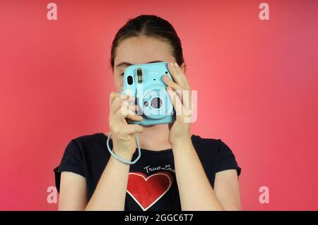 Femme jeune adulte tenant un appareil photo rétro. Caméra bleue Polaroid instantanée: FUJIFILM INSTAX Mini 11 Instant film Camera Banque D'Images